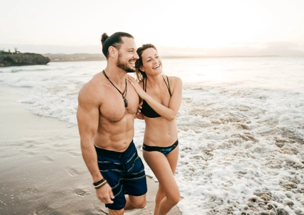 A couple on the beach with hair free bodies after a laser hair removal treatment