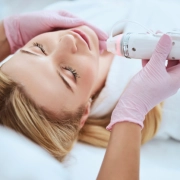 A woman receives a meticulous laser facial treatment focused on skin tightening, under the care of a professional wearing pink gloves.