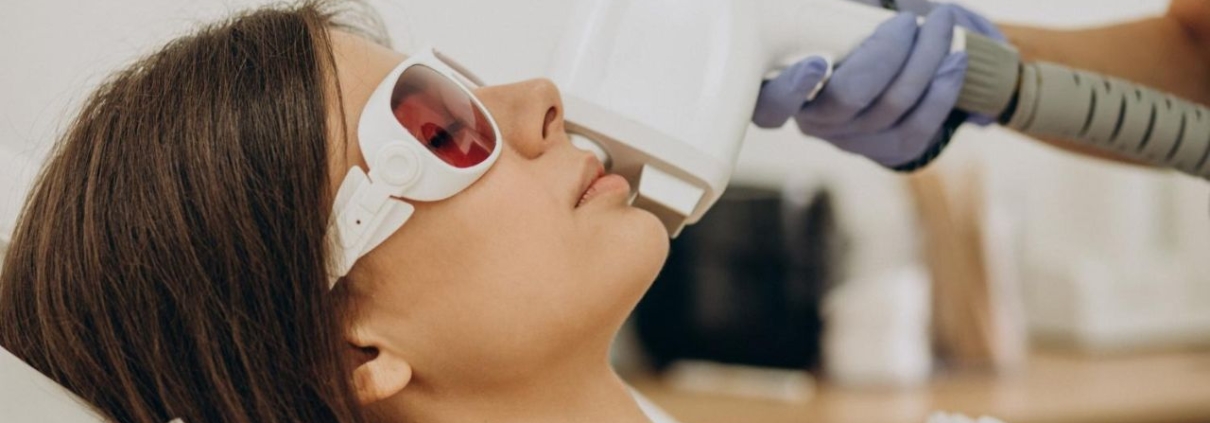 Woman lying down while a trained professional performs laser hair removal treatment on her skin