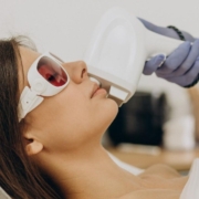 Woman lying down while a trained professional performs laser hair removal treatment on her skin