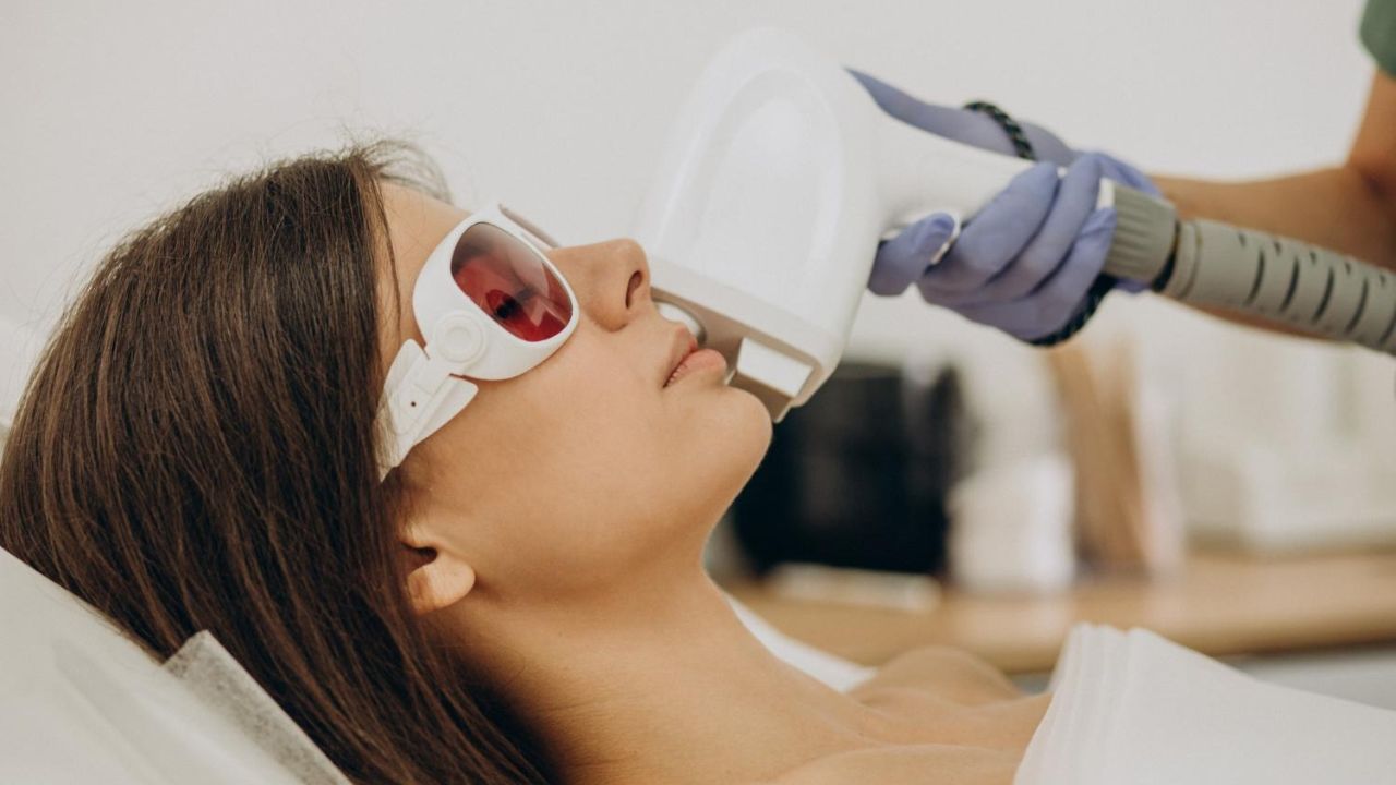 Woman lying down while a trained professional performs laser hair removal treatment on her skin
