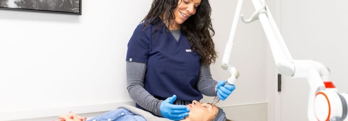 Skincare professional performing treatment in clinic with advanced equipment