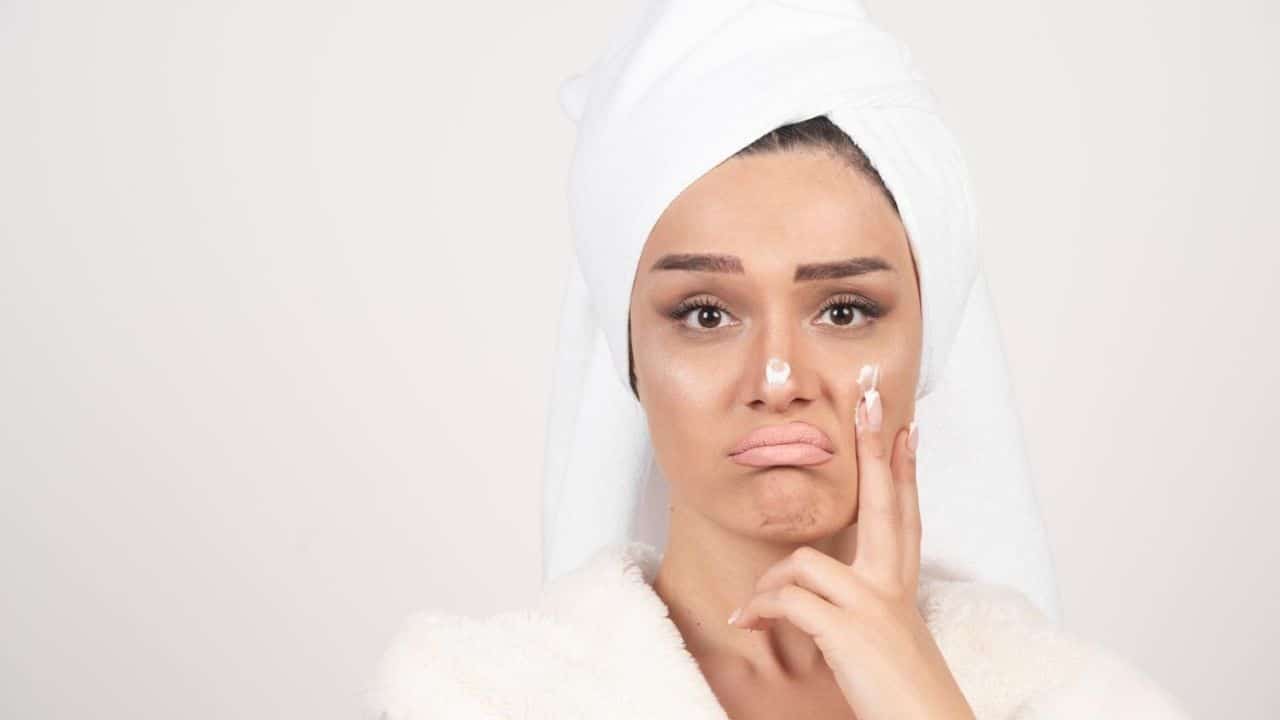Woman in a bathrobe applying cream of dull skin
