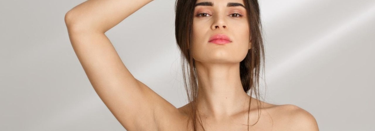 Woman standing with hand on forehead showing clean, smooth underarms