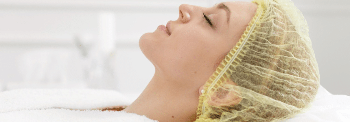 Woman receiving a facial treatment at a beauty clinic while lying on a treatment bed
