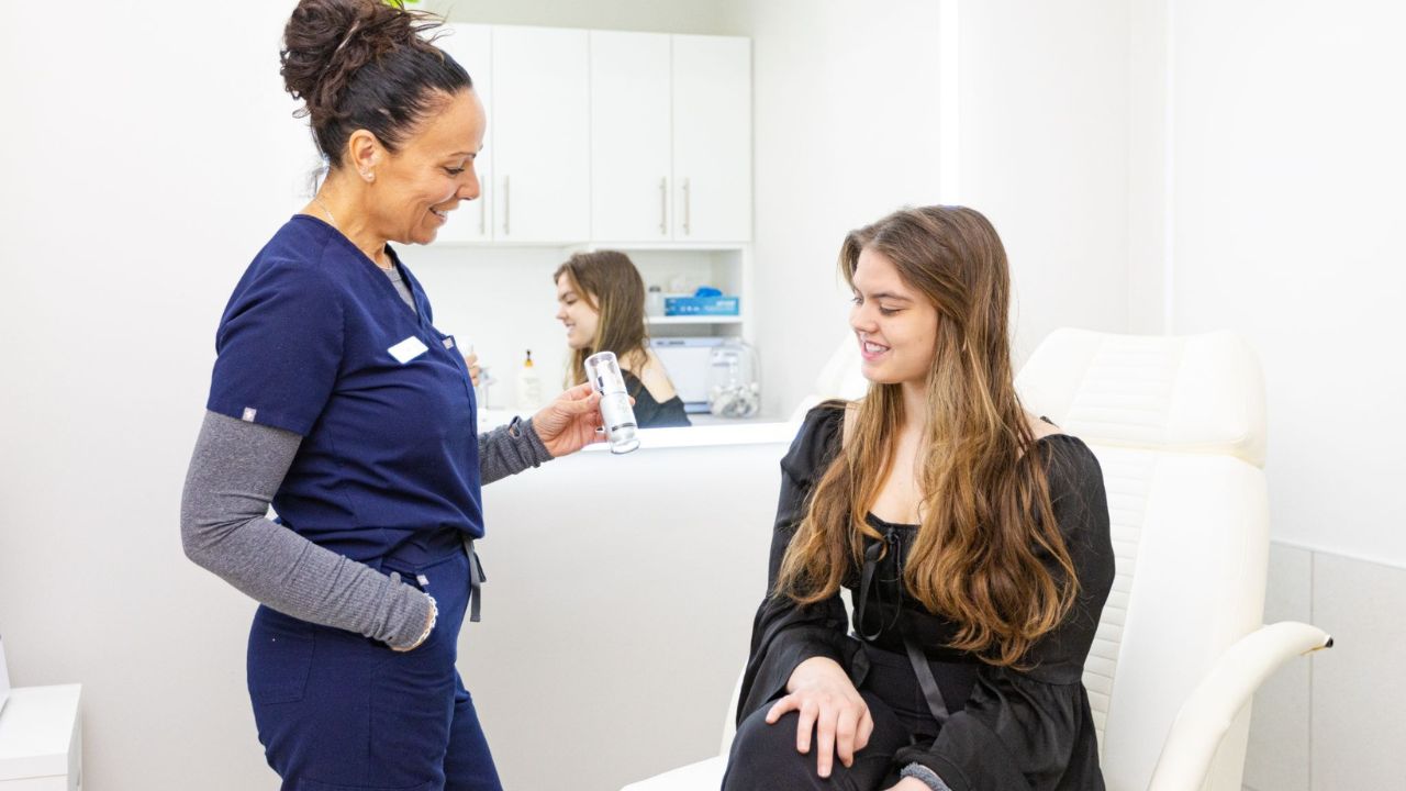 Professional recommending skincare products during post-treatment aftercare consultation in a clinical setting